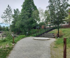 Kuva tapahtumapaikasta Tikkurilan Väritehtaanrannasta, jossa kiviset istumapaikat ja esiintymislavan kaltainen koroke.