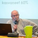 Jouko Jokisalo puhumassa pöydän takana mikrofoniin Pasilan kirjaston auditoriossa.