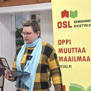 Camilla Kantola fasilitoi kirjoitustyöpajaa Marx-opistossa helmikuussa 2026, taustalla DSL:n roll-up.