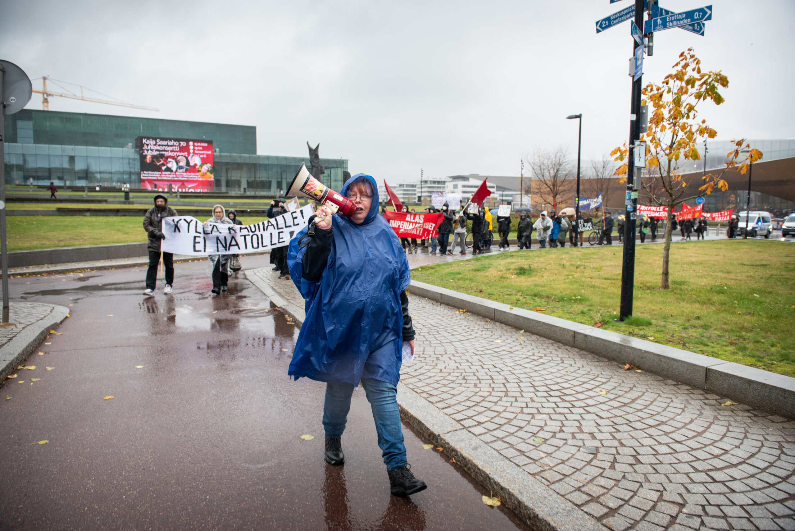 Henkilö johdattaa mielenosoituskulkuetta megafonin kanssa.